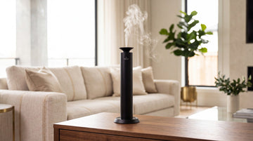 Black Aroma Max Mini Pro cold-air diffuser releasing a soft scent mist in an upscale living room