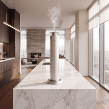 Aroma Max Mini Pro cold-air scent diffuser on a white marble kitchen island in a luxury home, scented mist rising